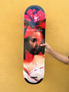 4Msb skateboard deck Bromeila with TIPtech, pro model for pro skateboarder Bruno Vinicius. Red, black and white graphic with a woman's face and the flower bromelia. The hand of pro skater Bruno Vinicius holding the deck in front of a yellow wall.