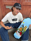4Msb pro skateboarder kilian zehnder with his pro model skateboard deck Cities. Kilian sitting outdoor on a stir in Stockholm with wooden doors behind, wearing a black 4Msb cap kilian zehnder graffiti and holding his new pro model skateboard deck showing the graphic: light blue background with motives of his four favorit cities.