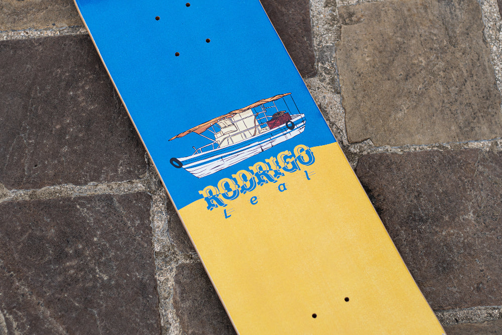 Skateboard deck, 4Msb Rodrigo Leal, blue and yellow with a boat motive, on a stone surface