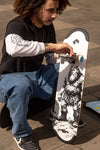 4Msb team rider Hadriel Junior, wearing jeans and black t-shirt, sitting on a skateboard deck while setting up the skateboard deck 4Msb Jättar (giants) with TIPtech in the street of Sao Paulo, Brazil. He's tightening the first truck with the blue 4Msb team wheels.