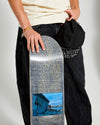 skateboarder holding a blue grey skateboard deck 4Msb graffiti Kilian Zehnder and a black cap graffiti Kilian Zehnder.