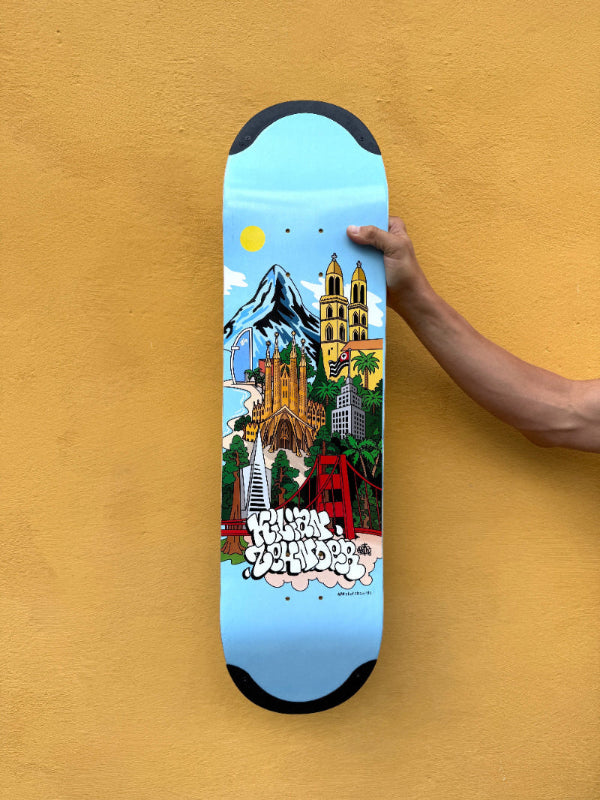 4Msb pro skateboarder kilian zehnder holding his pro model skateboard deck Cities in front of a yellow wall. The graphic: light blue background with motives of his four favorit cities, mountains, sun, bridges, towers, palm threes.