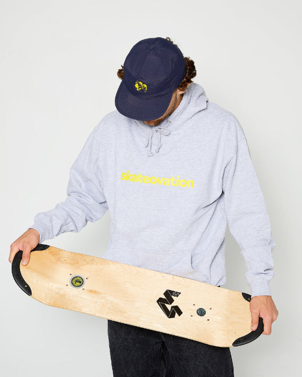 skateboarder wearing a navy blue 4Msb snapback cap with a yellow dala horse on the front, a heather grey skateovation hoodie core and holding a 4Msb skateboard deck with TIPtech in his hands.
