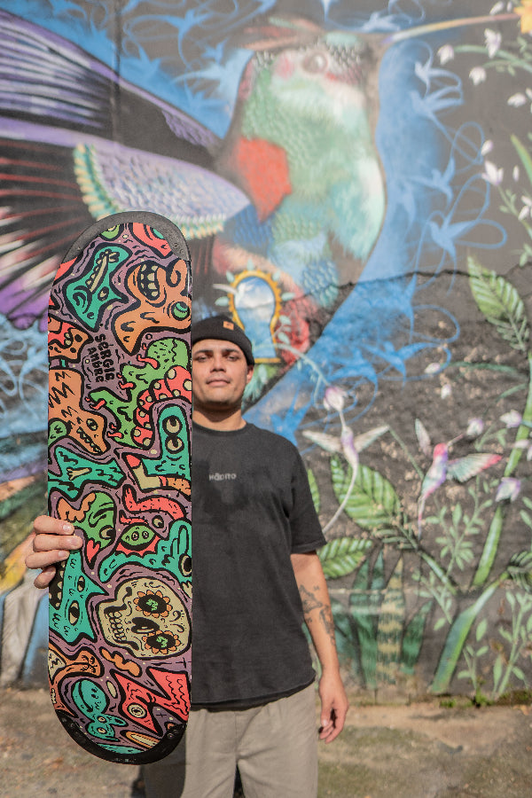 4Msb Pro rider Sérgio André with his signature skateboard deck Doodle Sérgio André with TIPtech infront of a colourful graffiti wall.