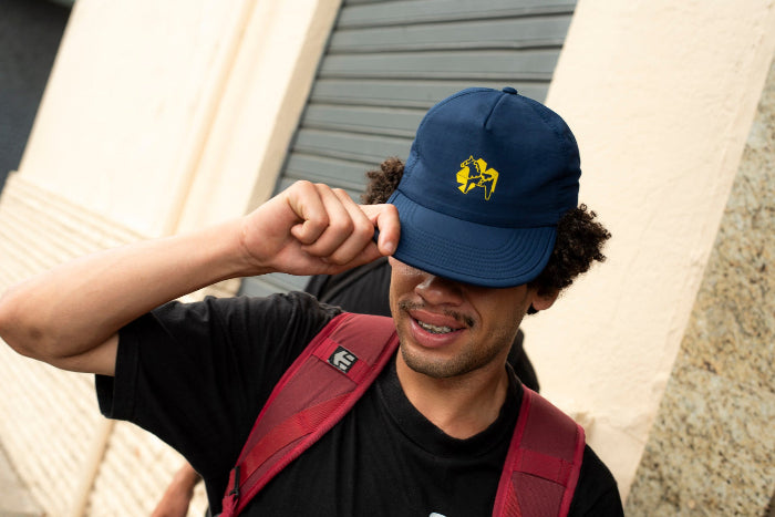 Pro skateboarder Bruno Vinicius wearing a navy blue 4Msb skateboard cap with a yellow dala horse on the front.