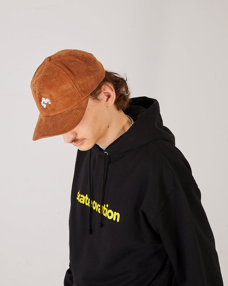 Skateboarder wearing a camel brown cord cap and black skateovation hoodie core with yellow text.