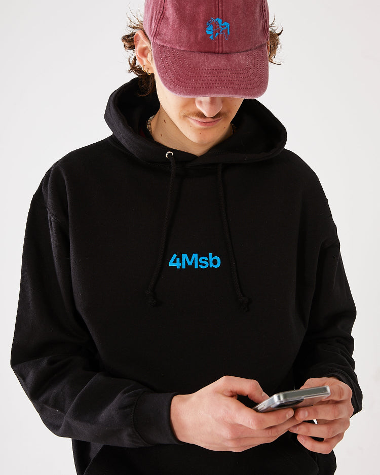 Skater facing forward looking at his phone, wearing a 4Msb dad cap dala horse vintage red and a black 4Msb hoodie dala horse.