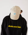 Skater wearing a black hoodie with 'skatevolution' text and a vintage sand coloured 4Msb dad cap dala horse.