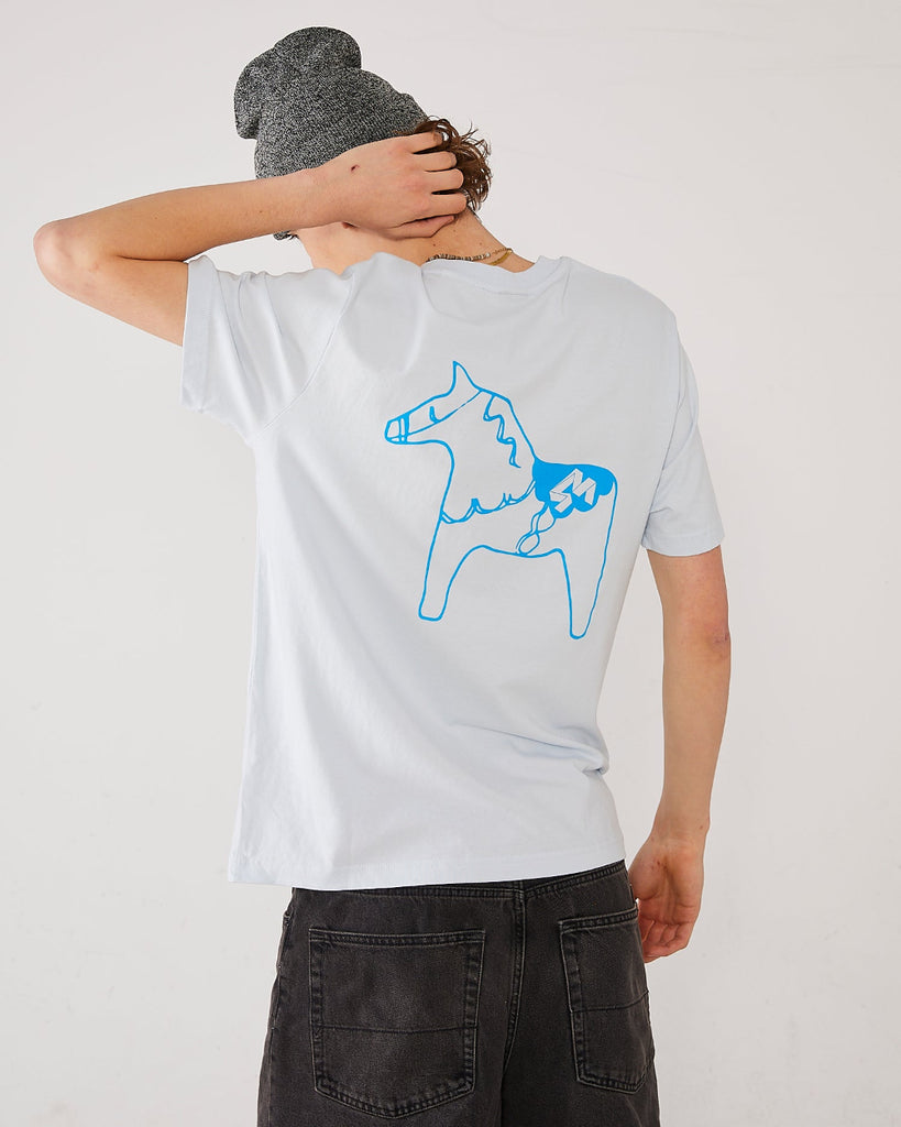 Skater wearing a light t-shirt with a blue dala horse on the back and a grey SO cuffed beanie.