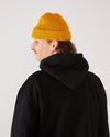 skater wearing a mustard yellow skateovation harbour beanie core and black hoodie (back).