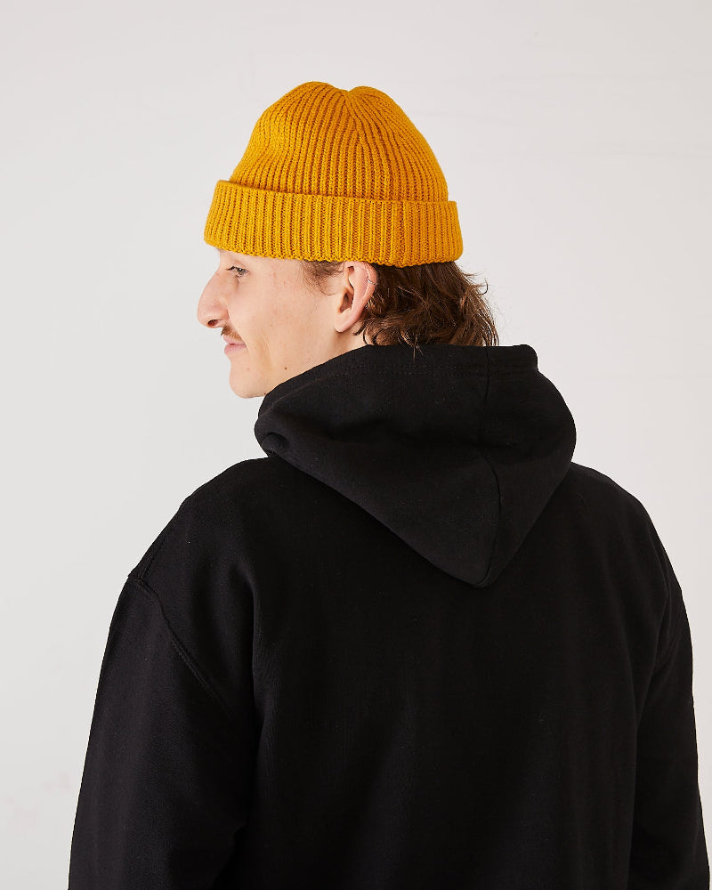 skater wearing a mustard yellow skateovation harbour beanie core and black hoodie (back).