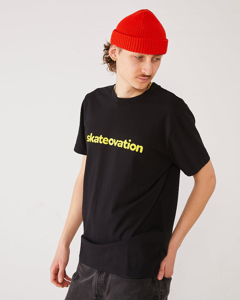 skater wearing a black t-shirt with 'skateovation' in yellow on the chest and a red harbour beanie 