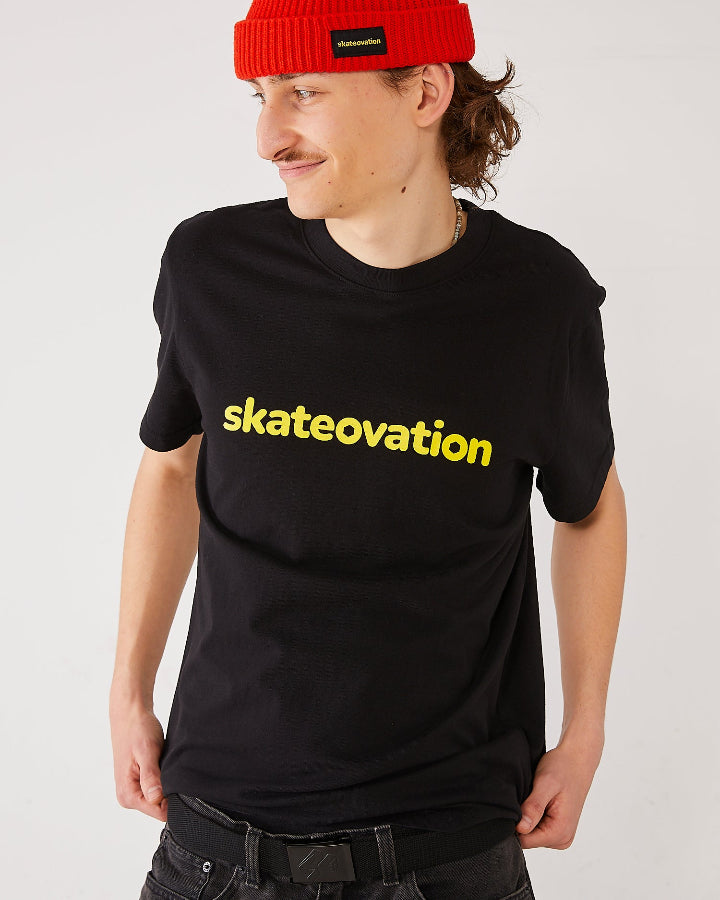 skater wearing a black t-shirt with 'skateovation' in yellow and a red harbour beanie 