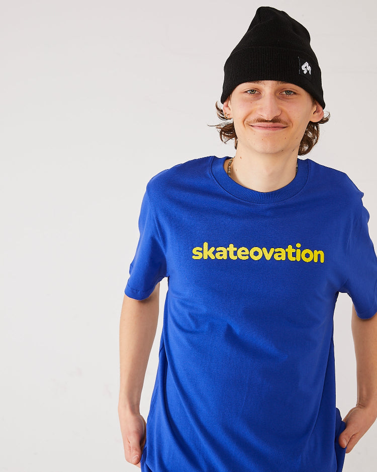 Skater wearing the Skateovation t-shirt Core in color worker blue with skateovation texted in yellow on the chest and a 4Msb cuffed beanie Quatro in black with the Quatro logo in white.