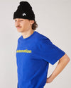 Skater wearing a Skateovation t-shirt Core in color worker blue, skateovation texted in yellow on the chest and a 4Msb cuffed beanie Quatro in black.