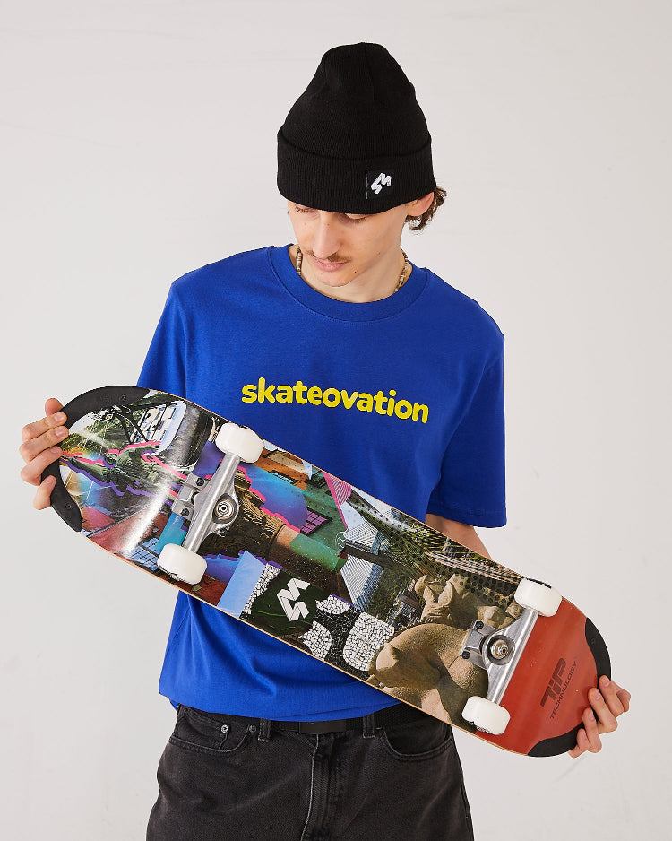 Skater wearing the Skateovation t-shirt Core in color worker blue, skateovation texted in yellow on the chest, a 4Msb cuffed beanie Quatro in black. Holding 4Msb TIPtech deck Collage Engelbrekt with 4Msb wheels Quatro in black and white.