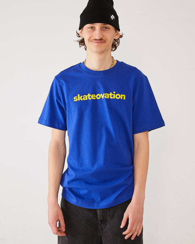 Skater wearing a Skateovation t-shirt Core in the color worker blue with skateovation texted in yellow on the chest and a 4Msb cuffed beanie Quatro in black.