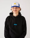 Skateboarder wearing a black 4Msb hoodie and a blue and white skateovation SO trucker cap.