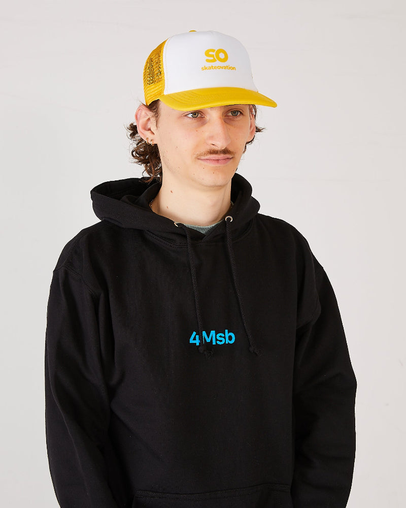 Skater wearing a black 4Msb hoodie and a white and yellow trucker cap SO.