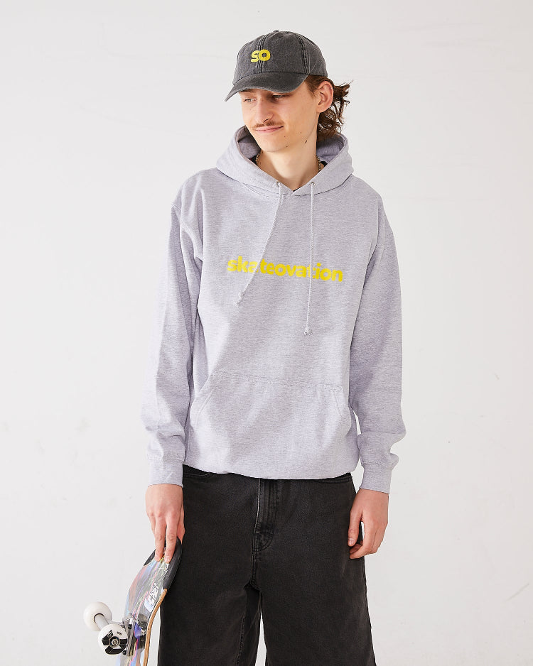 Skater wearing SO dad cap in vintage black with SO logo in yellow and a hoodie core in color heather grey with Skateovation texted in yellow on the chest.