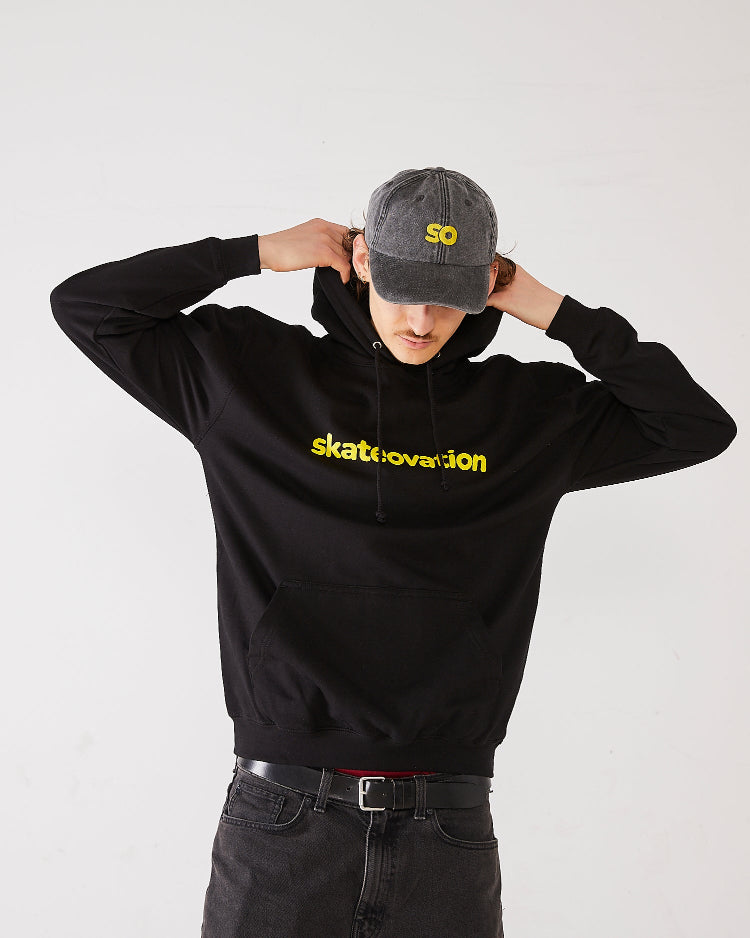 Skater wearing SO dad cap in vintage black with SO in yellow and a black hoodie with Skateovation texted in yellow.