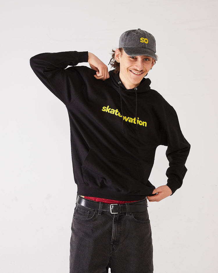Skater wearing SO dad cap in vintage black and a black hoodie core with Skateovation texted in yellow.