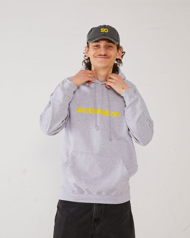 Skater wearing SO dad cap in vintage black with the SO logo in yellow and a hoodie in the color heather grey with Skateovation texted in yellow on the chest.