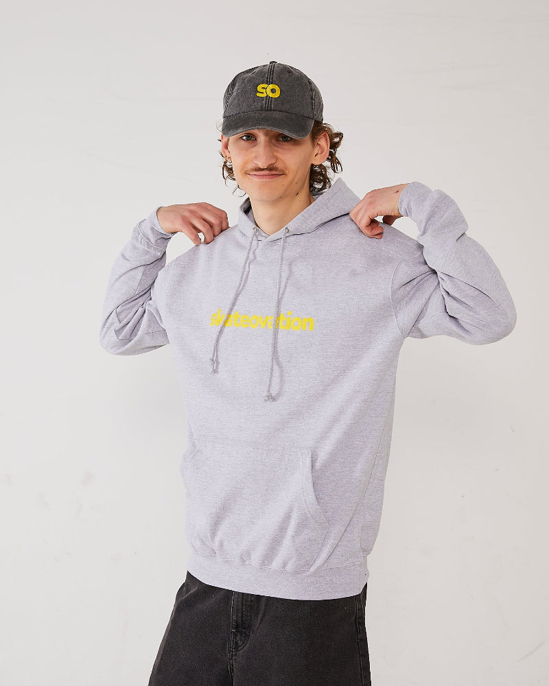 Skateboarder wearing a grey skateovation hoodie Edge with yellow text and a matching dad cap SO.