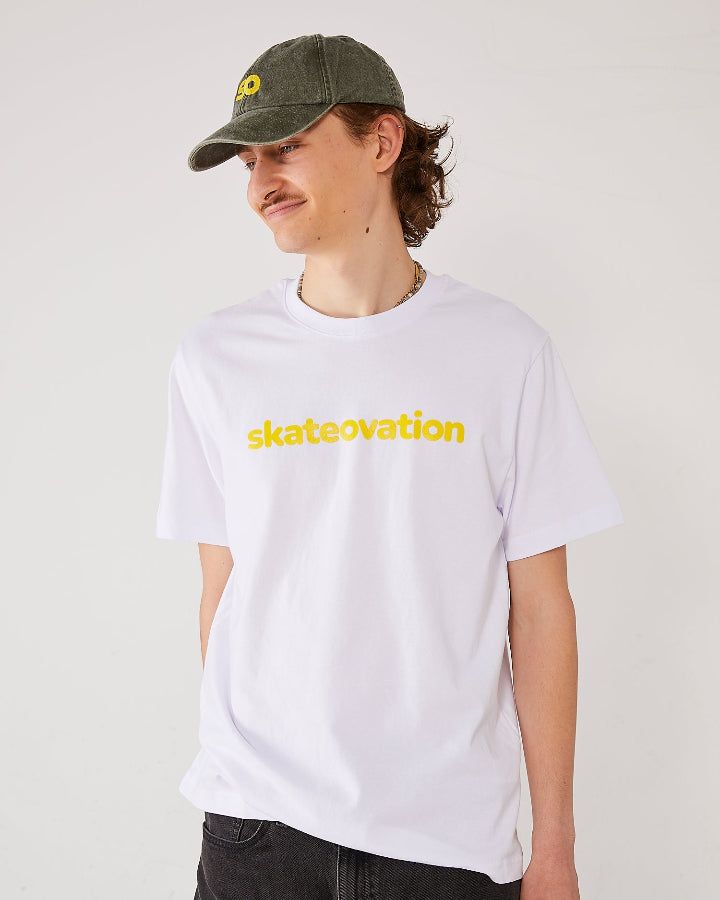 Skater facing forward, side, wearing a skateovation dad cap SO in the color vintage olive and a white T-shirt, core, with skateovation texted in yellow.