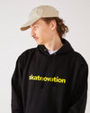 Skater wearing a black hoodie with 'skatevolution' text and a sand coloured 4Msb dad cap dala horse.