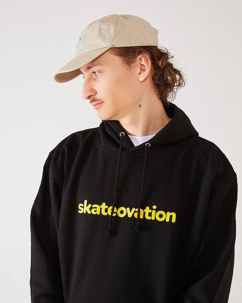 Skater wearing a black hoodie with 'skatevolution' text and a sand coloured 4Msb dad cap dala horse.