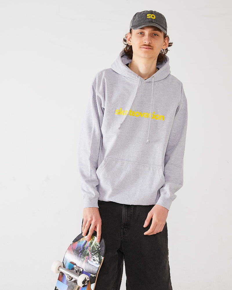 Skater wearing SO dad cap in vintage black with SO in yellow and a hoodie in the color heather grey with Skateovation texted in yellow.