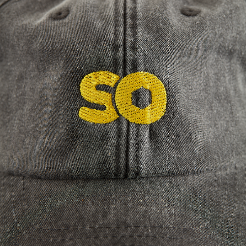 Vintage black dad cap close-up of embroidered 'SO' logo in yellow on the front.