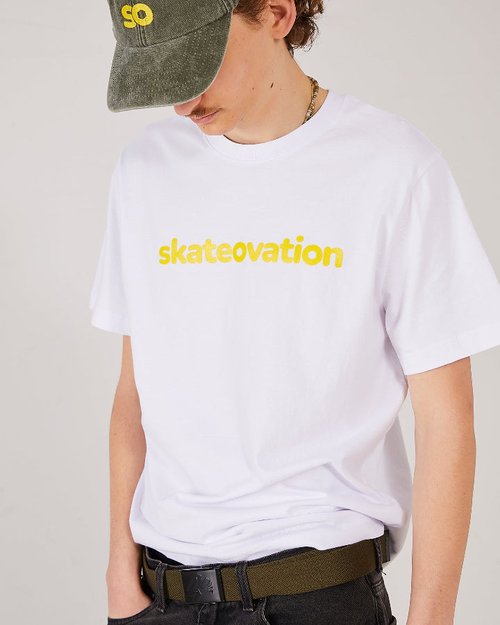Skater facing forward, side, hand in his front pocket, wearing a skateovation SO dad cap in the colour vintage olive, a white T-shirt with skateovation texted in yellow on the chest and a 4Msb webbing belt in the colour olive with a black buckle.