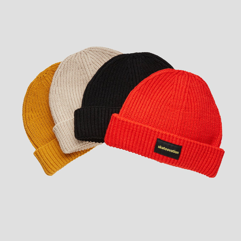 The Skatetovation harbour beanie core in four different colors: fire red (front), black, oatmeal and mustard (back).