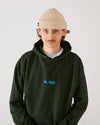 skaterboarder wearing a forest green 4Msb hoodie and a oatmeal beige skateovation harbour beanie core.