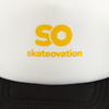 White and black trucker cap SO, close-up yellow 'skateovation' logo on the front.