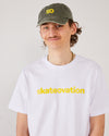 Skater facing forward wearing a skateovation dad cap SO in the colour vintage olive and a white T-shirt, core, with skateovation texted in yellow on the chest.