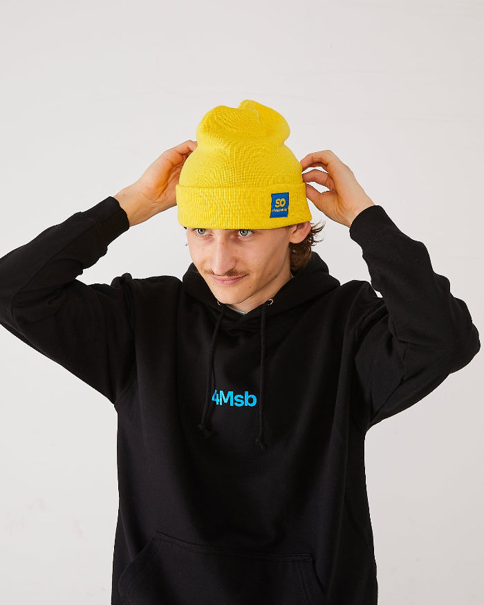 skater adjusting his beanie, a yellow SO skateovation cuffed one andd wearing a black 4Msb hoodie.