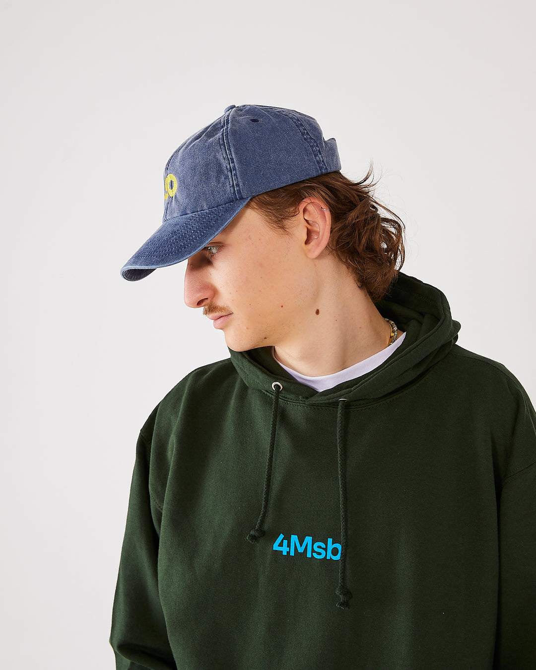 skater wearing skateovation so dad cap in vintage denim and a 4Msb hoodie dala horse in forest green.