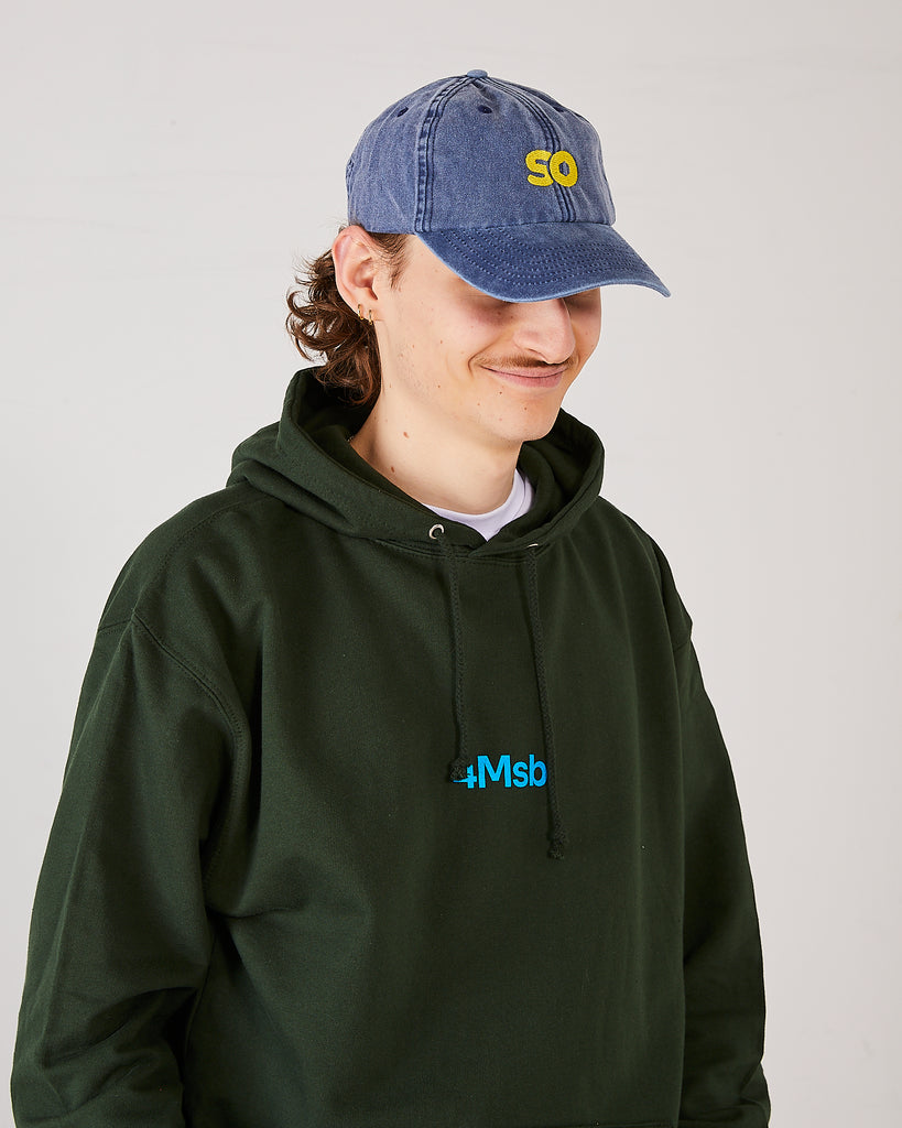 skater wearing skateovation so dad cap in vintage denim and a 4Msb hoodie dala horse in forest green.